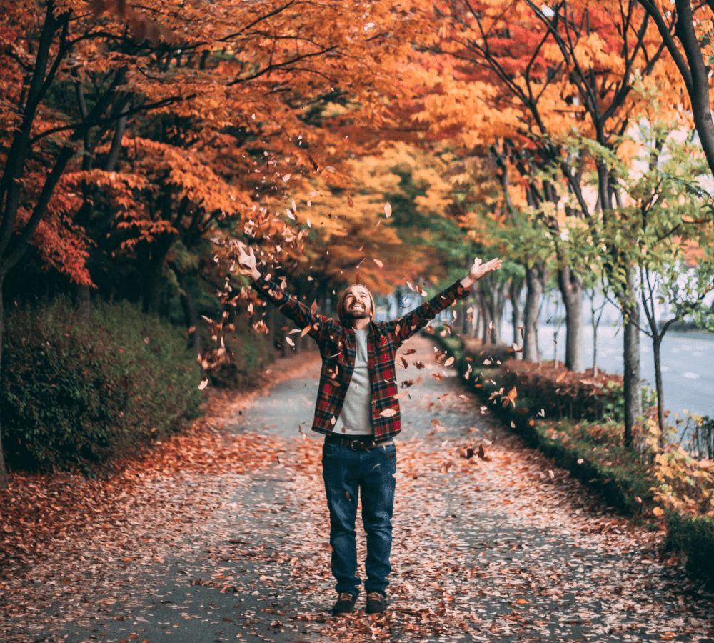 Man standing under a fall tree and smiling