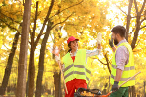 A man and a woman raking leaves and high-fiving.